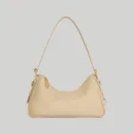 Front view of minimalist beige leather shoulder bag with adjustable strap and gold hardware