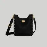 Close-up macro view of the rectangular gold turn-lock closure on the minimalist black studded shoulder bag