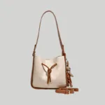 Front view of elegant color-block bucket bag featuring cream croc texture and a playful animal charm