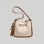 Back view of elegant color-block bucket bag featuring cream croc texture and a playful animal charm