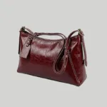 Side view of vintage red vegan crossbody tote showing adjustable strap and brass hardware.