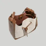 Open interior view of cream and brown crossbody bucket bag with magnetic snap closure and soft lining