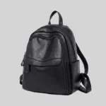 Angled view of black multi-pocket urban backpack highlighting front flap pocket and soft structure