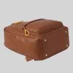 Bottom view of structured top-grain leather commuter bag base featuring four gold-tone metal protective feet to prevent wear and tear.