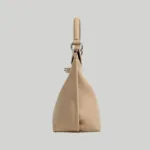 Gusseted side profile of beige quiet luxury top handle bag with silver hardware