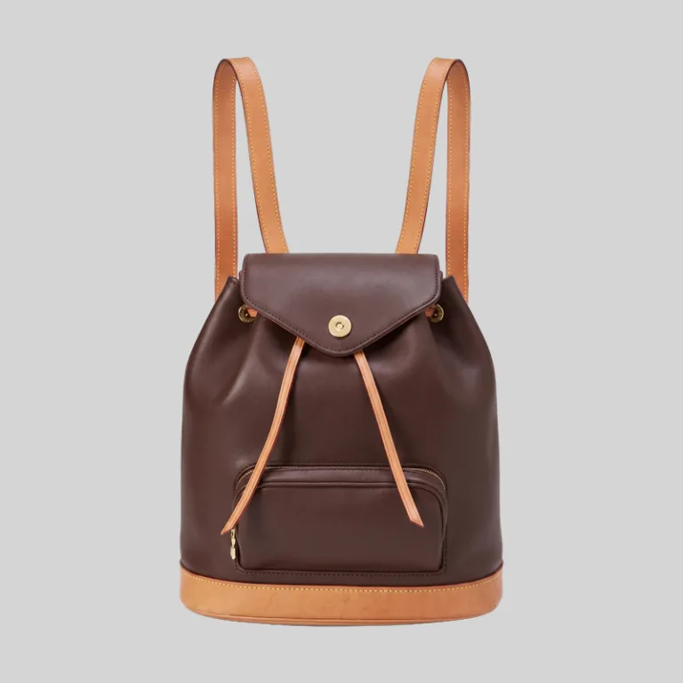 Front view of quiet luxury dark brown and tan leather rucksack with magnetic snap flap closure.
