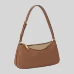 Side angle view of brown underarm bag showcasing gusset structure and gold-tone zipper hardware