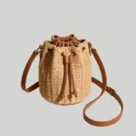 Structured woven straw crossbody bucket bag with brown faux-leather drawstring pouch