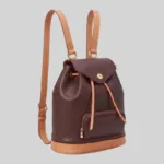 Angled front view of structured leather commuter backpack with drawstring closure and front zip pocket.