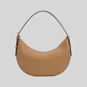 Front profile of a tan half-moon commuter bag featuring gold-tone hardware, top zip, and an adjustable strap.