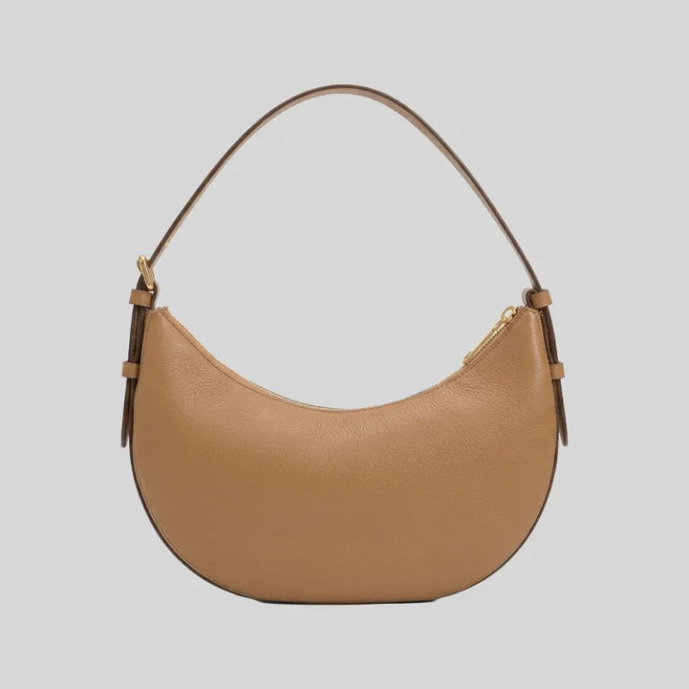 Front profile of a tan half-moon commuter bag featuring gold-tone hardware, top zip, and an adjustable strap.