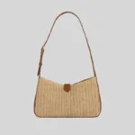 Front view of woven raffia underarm bag featuring brown leather trim and curved silhouette