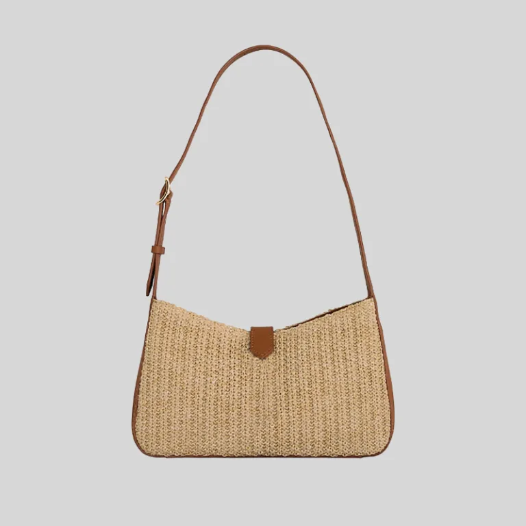 Front view of woven raffia underarm bag featuring brown leather trim and curved silhouette