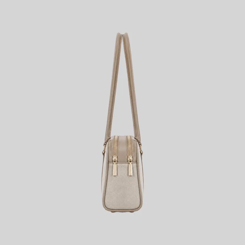 Side profile of the structured beige East-West shoulder bag highlighting dual top zippers and gold-tone hardware.