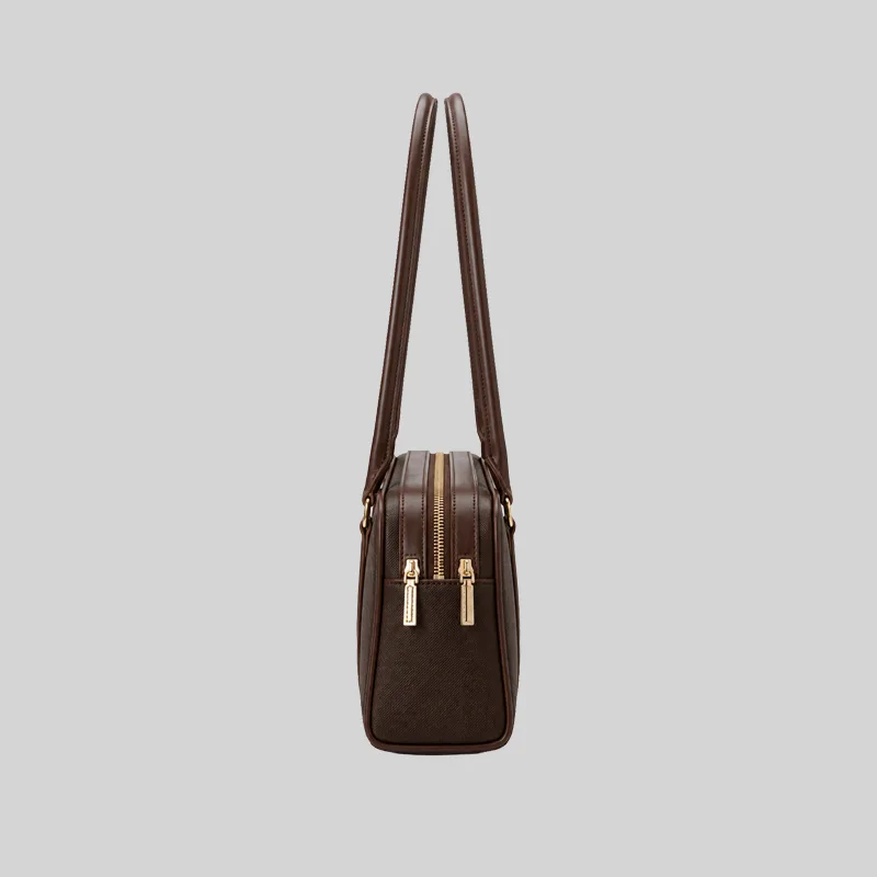 Side profile of the structured dark brown East-West shoulder bag highlighting dual top zippers and gold-tone hardware.