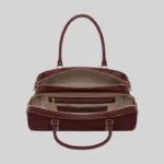 Top open view of the burgundy shoulder bag showing dual compartments, interior lining, and zip pockets
