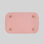 Structured bottom view of the pink satchel featuring four protective metal feet on a smooth pink base.