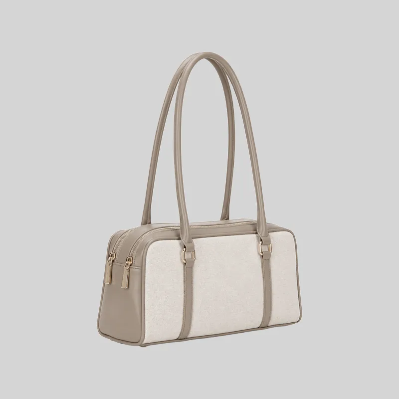 Side view of the structured commuter shoulder bag showing the double zip closure and gold-tone hardware, beige