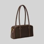 Side view of the structured commuter shoulder bag showing the double zip closure and gold-tone hardware, dark brown
