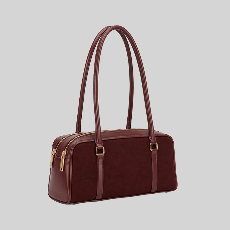 Side view of the structured commuter shoulder bag showing the double zip closure and gold-tone hardware, burgundy